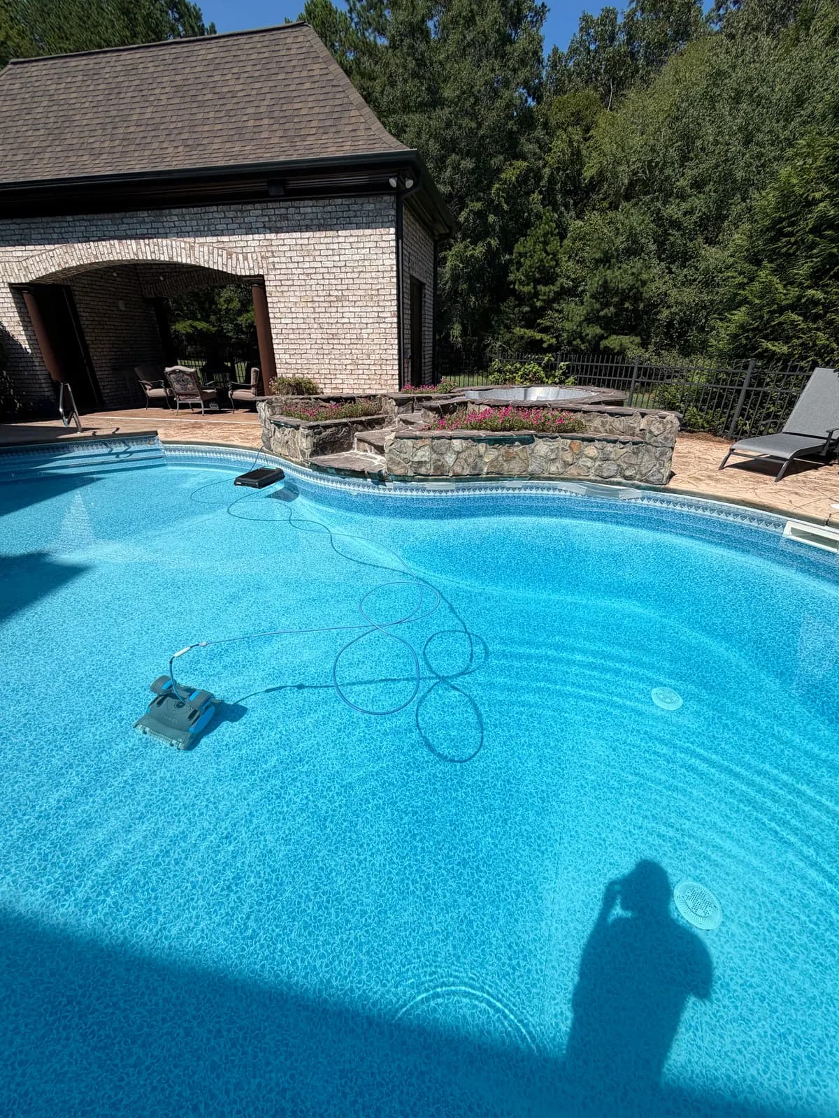 Freeform pool by a pool house with an automatic cleaner